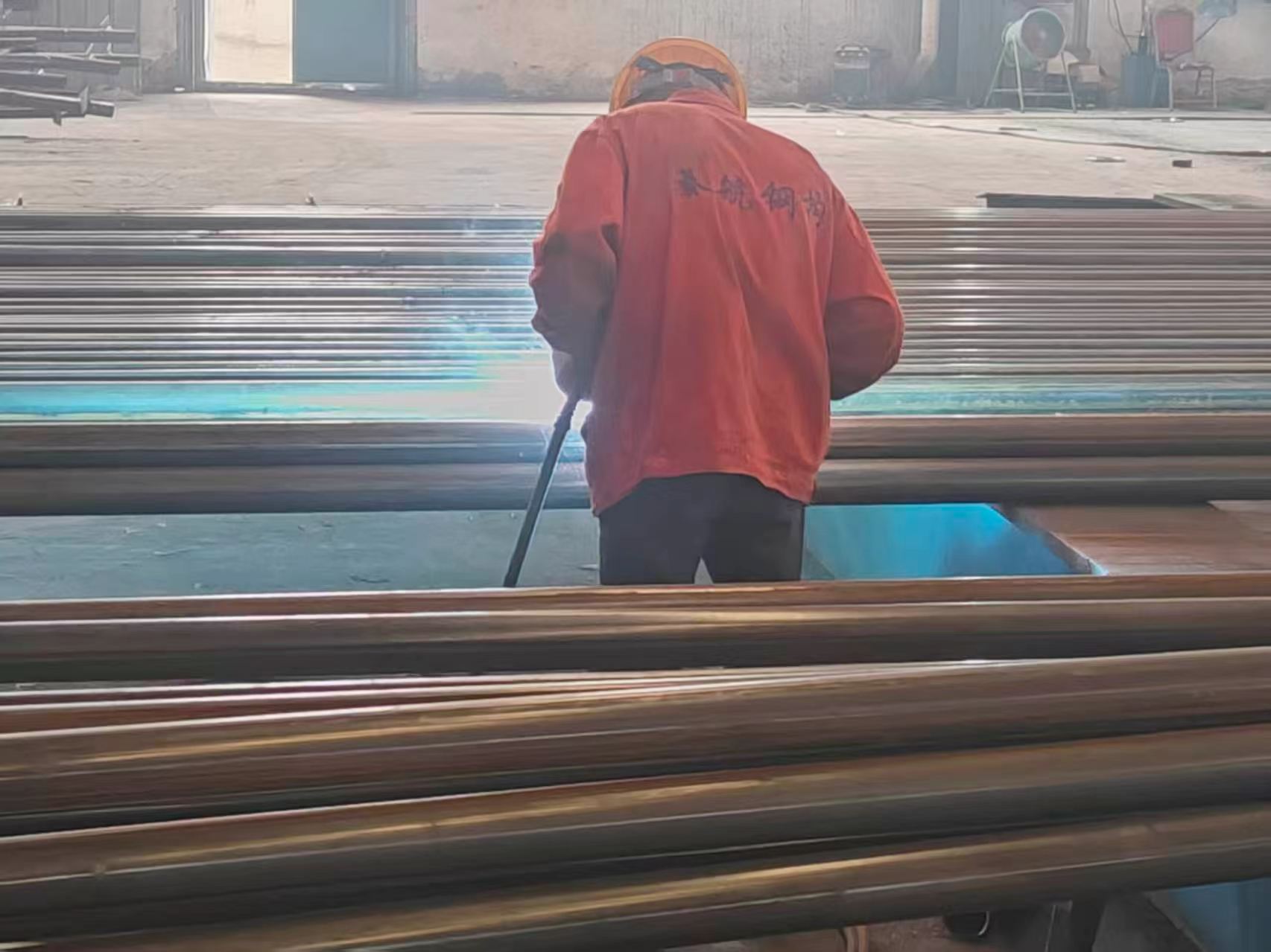Steel cutting and welding work on structural members inside a steel fabrication workshop