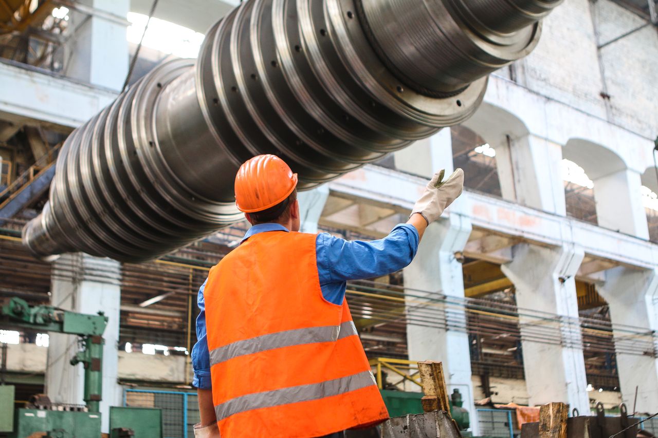 Worker performing surface painting and coating on steel structure components in a fabrication workshop