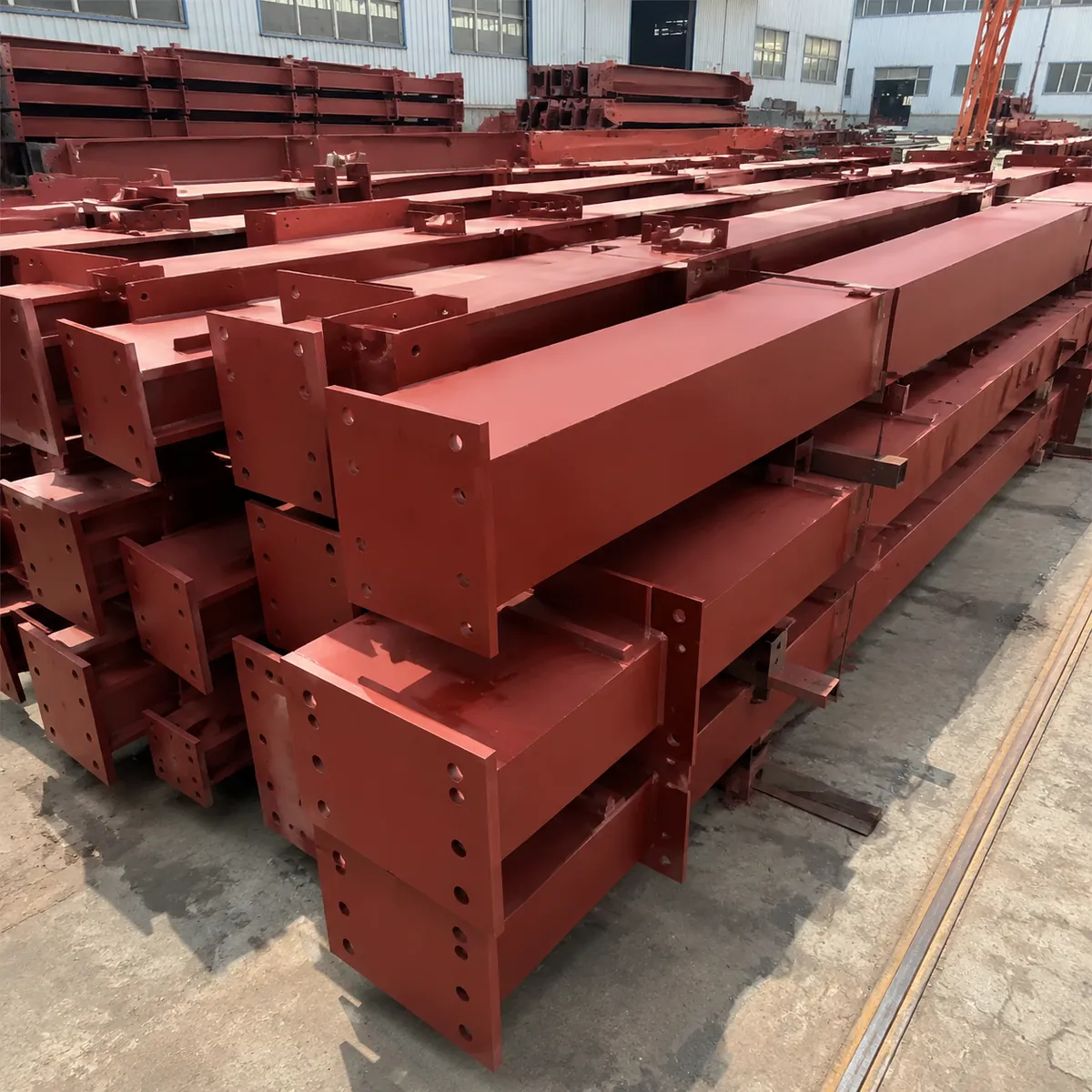 Fabricated steel portal frame members stacked after painting in factory yard