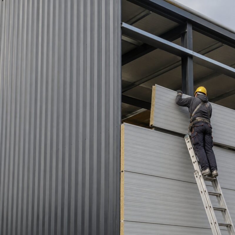 Steel building cladding panels being installed on warehouse
