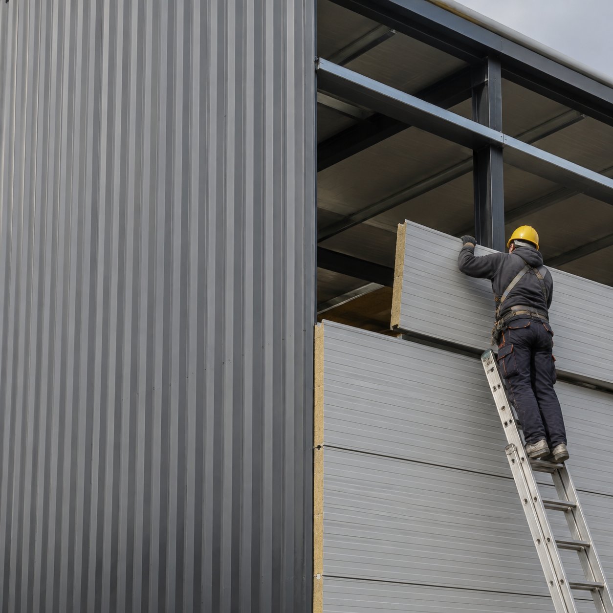 Steel building cladding panels being installed on warehouse