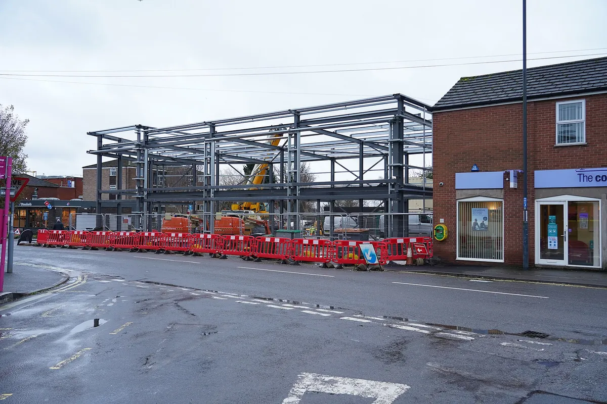 Steel roof members being lifted and fitted onto a building frame during erection