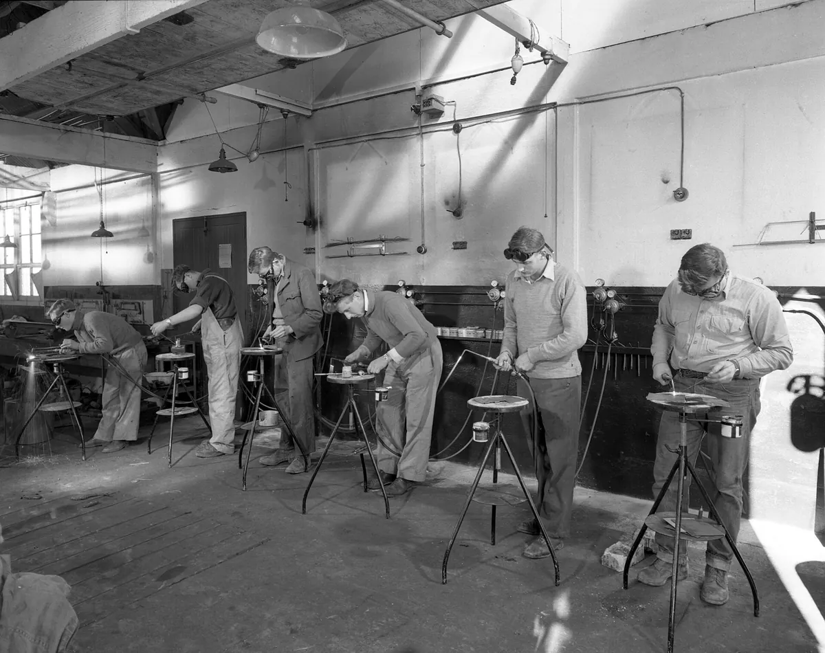 Welder joining structural steel members in a fabrication workshop